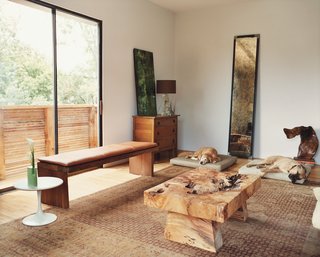 In the living area, the family’s dogs Kirby and Forest commandeer beds that Matt custom designed for them, enjoying the view of the trees floating outside the floor-to-ceiling windows reflected in the recycled steel-frame mirror. 