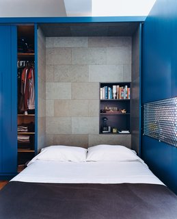 The interior of the Murphy bed compartment is lined with a stained cork panel and contains a smaller shelving unit for bedside reading, alarm clock, and reading lamp.