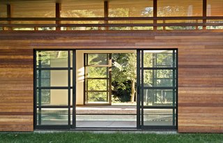 Skinny Dip - Photo 3 of 3 - Sliding glass doors open to reveal the interior of the pool house, which boasts a line of clerestory windows just below the roof.