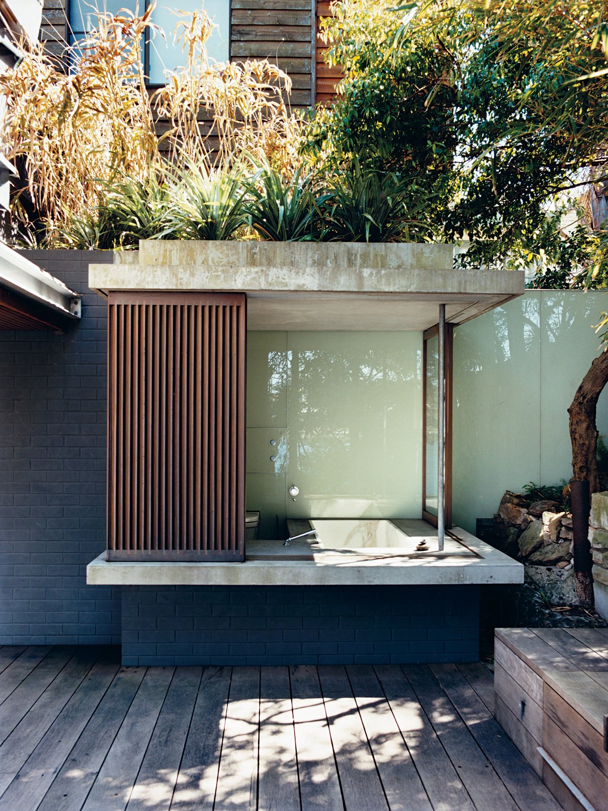 The glass and wood walls of the bathhouse, like other retractable panels on the house,
offer shade with a view.