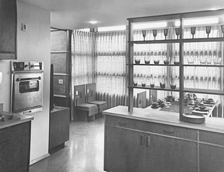 Interior of a prefab house showing kitchen looking out into dining room, designed by Frank Lloyd Wright.