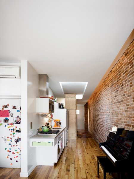 From the living room, the narrow apartment stretches back into the sleeping quarters by way of a compact kitchen that packs all the needs of a home chef against one wall.