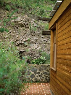 The steep canyon wall rises directly behind the house.