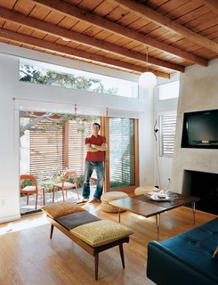 Casa Study House #1 - Photo 1 of 10 - Architect, builder, and developer Jeremy Levine stands at the threshold of the front deck and the living room under his newly raised ceiling made of wood recycled from the original pitched roof.