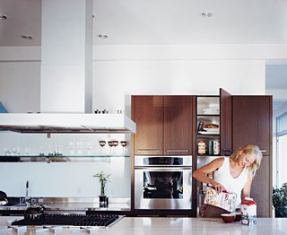 Jill prepares breakfast in the custom kitchen, which features a Roman travertine-topped work island.