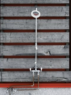 A stop at the outdoor shower reveals the red steel frame beneath the wooden siding.