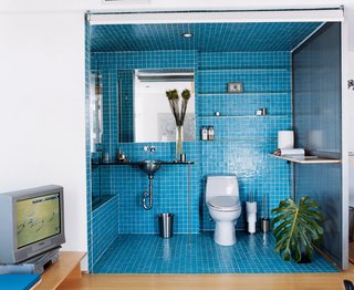 A roll-down shade encloses a guest bath on the lower level. The bath tile is two-by-two Daltile mosaic. The sink is from Kroin.