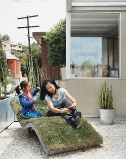 How This Couple Broke The Rules in a LA Suburb - Photo 5 of 9 - Téa gets mom ready for her close-up on the curvy nature-meets-industry chaise lounge of the architects’ own design. The landscaping in front and out back is characterized by sturdy, resilient, and drought-resistant plants like bamboo and cacti, cultivated in galvanized steel planters.