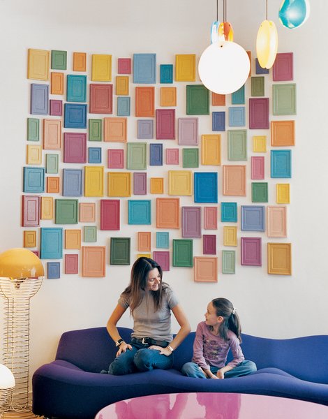 Clémence and daughter Clara, nine, relax on a purple Pierre Paulin 261 sofa below an installation by artist Alan McCollum. A small family of Verner Panton 1969 Wire lamps, featured in the inaugural Kreo exhibition, live to the left.