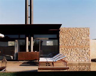 Labics took their design cues from the original structure’s history and function: The form of the industrial-looking double chimney, for example, was derived from an old stack placed on an adjacent farm. For the water feature, at right, a moat-like trench surrounding the house was dug to reduce humidity in the foundation.
