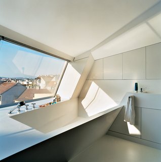 The cavity for the bathtub is part of the same continuous form-world as House Ray 1’s sloping roofscape. The white tub is made from Corian; the faucet is by Dornbracht.