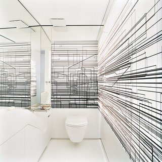 The walls of the toilet room are decorated with an abstract composition of overlapping black lines printed on a screen that is lit from behind.