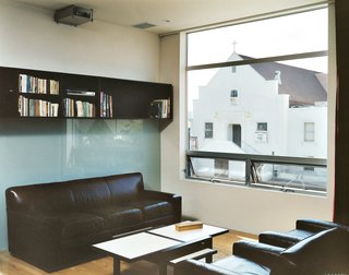 All the west-facing windows frame the church across the street. Bookcases, also designed by MS-31, line the back wall. When the chairs and couch from Restoration Hardware face each other, it’s a cozy little living room. Turn the chairs around and it’s a full theater complete with an 11-by-17-foot image projected on the wall.