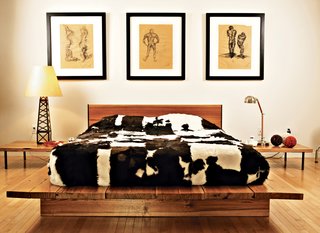 Home Cooking - Photo 3 of 8 - Graphic cowhides on the guest bed, the dining chairs, and the living room floor unite the varying levels of the house. That design element—and the cute oil derrick lamp in the guest bedroom—remind you that, yes, you are in Texas. The drawings are by Erik’s brother Jair, an architect working in New York.