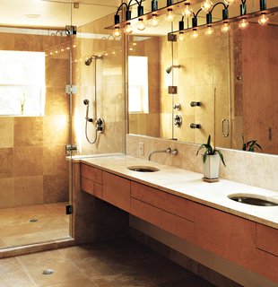 Home Cooking - Photo 6 of 8 - The master bath is a simple rectangle. "Like the kitchen, I designed it so that no stuff was laying around," Erik said. The surfaces are natural and subdued; a simple palette of tones, colors, and materials unifies the space. Travertine marble was used on the floors, shower, and countertop. The closet and cabinetry are maple. Erik designed the light fixture himself because, he says, "there was nothing I could find that fit the scale of the room." He used cold-rolled steel with exposed wires to give it an industrial feel.
