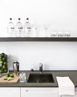 The wet bar at the end of the kitchen is equipped with a spout for filtered water, ice maker, wine fridge, and over-sink shelving--and is the happy-hour hotspot.Photo by <br><br>Ben Mayorga Photography