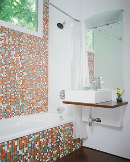 The Shipping Muse - Photo 2 of 23 - Robertson--with the help of developers Katie Nichols and John Walker, who were heavily involved in the design process--finished the guest bathroom with Modwalls tiles and a sink they found on eBay. They used a piece of marine plywood, leftover from building the front-porch steps, to create a counter on which the sink could sit--and where the family can rest their toothbrushes. To the right of the sink is a Toto dual-flush toilet, which is great for conserving water but has proven problematic for toilet training, as American potty seats aren't designed to fit these Japanese basins.