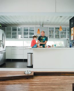 The Shipping Muse - Photo 4 of 23 - In the kitchen proper, Freeman fixes a snack while son Eli plays on the counter, one of his favorite spots in the house, second only to the kitchen steps.