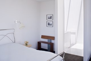 Noe Valley Renovation - Photo 5 of 17 - Back in the master bedroom, the designers installed Tolomeo wall sconces by Artemide next to the bed and placed a bench next to the door made by Hart's uncle, Peter Czuk of Czuk Studio. The bedroom door, which is rarely closed, is the starting point for the continuous flow of movement and light from the top of the house to the main level and down to the bottom floor.<br><br>Photo by <br><br>Sharon Risedorph