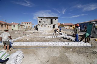Luyanda Mpahlwa - Photo 1 of 9 - Before building the framework of the house with pine timber and galvanized metal, the workers piled sandbags on the ground to map out the home’s foundation. Image courtesy Interactive Africa/ Design Indaba