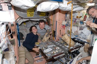 NASA astronaut Nicole Stott and Russian cosmonaut Roman Romanenko, both Expedition 20/21 flight engineers, are pictured at the galley in the Unity node of the ISS. Canadian Space Agency astronaut Robert Thirsk, Expedition 20/21 flight engineer, is mostly out of frame at right. Photo taken October 5, 2009. Image courtesy of NASA.