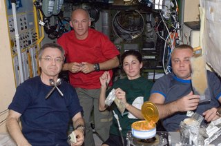 Canadian Space Agency astronaut Robert Thirsk (left), NASA astronauts Jeffrey Williams and Nicole Stott; along with Russian cosmonaut Maxim Suraev, all Expedition 21 flight engineers, share a meal at the galley in the Zvezda Service Module of the ISS. Photo taken October 12, 2009. Image courtesy of NASA.