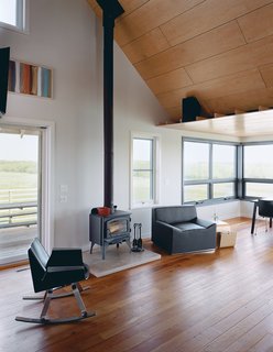 A Blu Dot Buttercup rocker and armchair sit next to the wood-burning stove set on a limestone slab from Stone City, Iowa—a city famously captured by the painter Grant Wood, who grew up in that area.