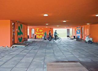 The communal entrance beneath the building is known as the "public square"; sisters Tessa and Anne Bouwmeester and a friend set off on their bikes.