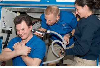 A haircut, performed by Tim Kopra for Roman Romanesko, calls for clippers connected to a vacuum to entrap cut hair. Image courtesy of NASA.