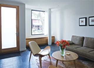 Just through the front door is the living room where built-ins by Chong share space with a three-legged Wegner chair and photo-graphs by Arnaud Maggs.