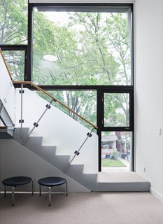 The second-floor family room is fronted by an L-shaped staircase with an opaque guardrail that provides some privacy for the front facade.