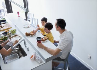 The family shares a meal at the counter in the kitchen.