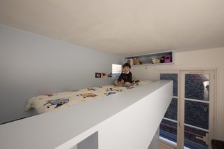 A multitude of shelves and storage let Eva hide her stuffed animals, books, and secret notebooks -- with a small corner looking out of the window onto the Paris landscape outside and the window to her brother inside.