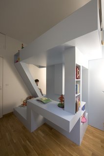 The bed seems to soar above the playing space, held up by bookshelf columns and a carefully angled staircase.