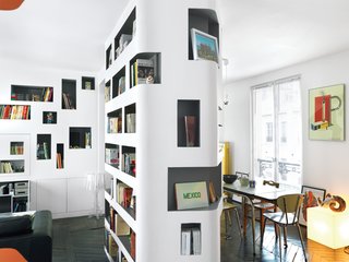 H2O Architectes used curvy cutouts in the space’s central column to draw the eye around its corners. A clever recessed cupboard conceals the TV screen. Comics, clearly, are everywhere.