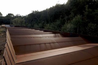 The roofline of the winery structure is defined by a sequence of parallel steel blades.