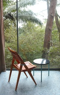 Lina Bo Bardi - Photo 10 of 14 - Her folding side chair, against the floor-to-ceiling window wall of the Glass House. Photo courtesy Espasso.