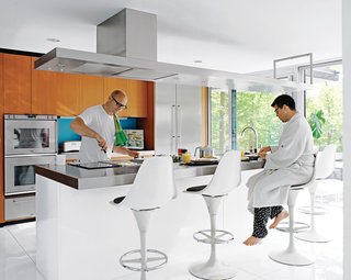 Despite their fidelity to the original structure, the residents made small changes, notably in the kitchen: The wood-veneered island was moved to create more circulation space behind it and finished in white lacquer and stainless steel. Wood cabinetry above the island was exchanged for a steel ventilation unit.