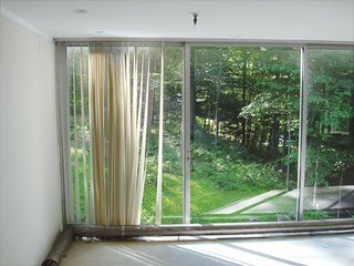 A previous owner, rather than replacing the imploded air vents in the cement slab, had installed radiators, chewing up the diminutive white ceramic tiles and ruining the visual impact of the glass.