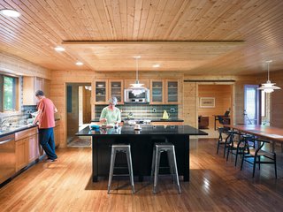 In the kitchen, Danish PH 5 lamps illuminate the island and table. The lined wood planks on both the ceiling and floor draw the eye naturally through the space to the study beyond, where Keith’s father’s original Jens Risom desk resides.