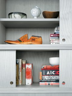 A Clean Slate - Photo 3 of 5 - The cabinet doors of the living room wall unit, in birch veneer painted a calming gray, slide with silken ease but never fully close, leaving strategic gaps for the display of Jun’s eclectic array of books and objects.