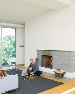 Christian and Jack play chess by the fireplace - the centerpiece of the living room and which the Arnolds use daily during the winter. The hearth is made of large slabs <br><br>of limestone, which Christian cut himself, intentionally leaving imperfections on the surface for texture. A studio8 couch and Vitra Tom Vac Rocker articulate the space.