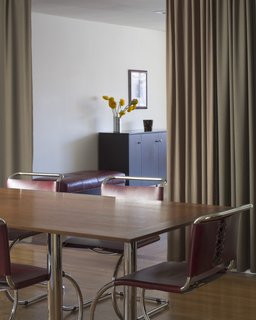 As you look through the curtained divider between the living and the dining room, you see a long wall extending toward the windows in the living room. Apparently when Mrs. Schiff had Neutra design the place in the mid-30s it was largely to suit the specifications of her furniture. Where the hutch in the background now sits was a massive entertainment console with a humidor and all manner of fun. Photo by Mark Darley.
