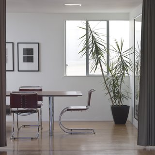 The dining room is lit in part by this frosted window that actually looks out into something of a dead zone between the building and the one next door. Nonetheless, the diffuse glow warms the place up. The steel tube chairs continue the Bauhaus vibe and pick up on the metal window frames and railing. Photo by Mark Darley.