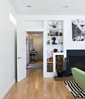 Ewing used Canadian maple for the hallway and living-room floors, giving them a bright, clean look. A built-in shelving system borders the hearth, creating functional and decorative storage spaces for firewood collected on-site.