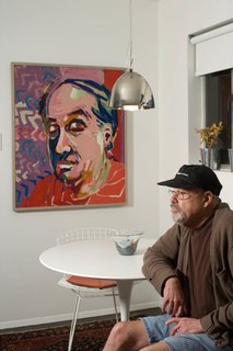 Ronald Popp, with a self-portrait in the dining zone off the kitchen. The Harry Bertoia chairs are from his existing collection; their orange pads served as the design springboard for the kitchen cabinetry. Popp acquired the Eero Saarinen table for the space.