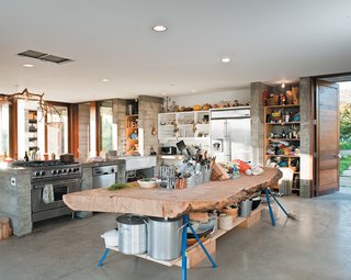 A massive slab of cypress perched atop sawhorses provides storage for pots and utensils.