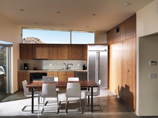 One large room houses the kitchen, dining, and living area; the backsplash and countertops are made by Vetrazzo.