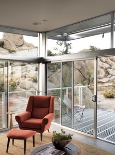 The main living area extends to the deck through sliding glass doors. The orange David Chair and ottoman were designed by Palm Springs-based interior designer Christopher Kennedy and are from his eponymous line of furniture. Kennedy did the interior design for the whole house, playing a large role in choosing the decor and eco-friendly surfaces.