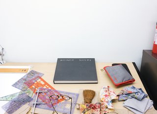 A collection of objects from Lawrence’s desk include stencils, paint rags, glasses, and a notebook.